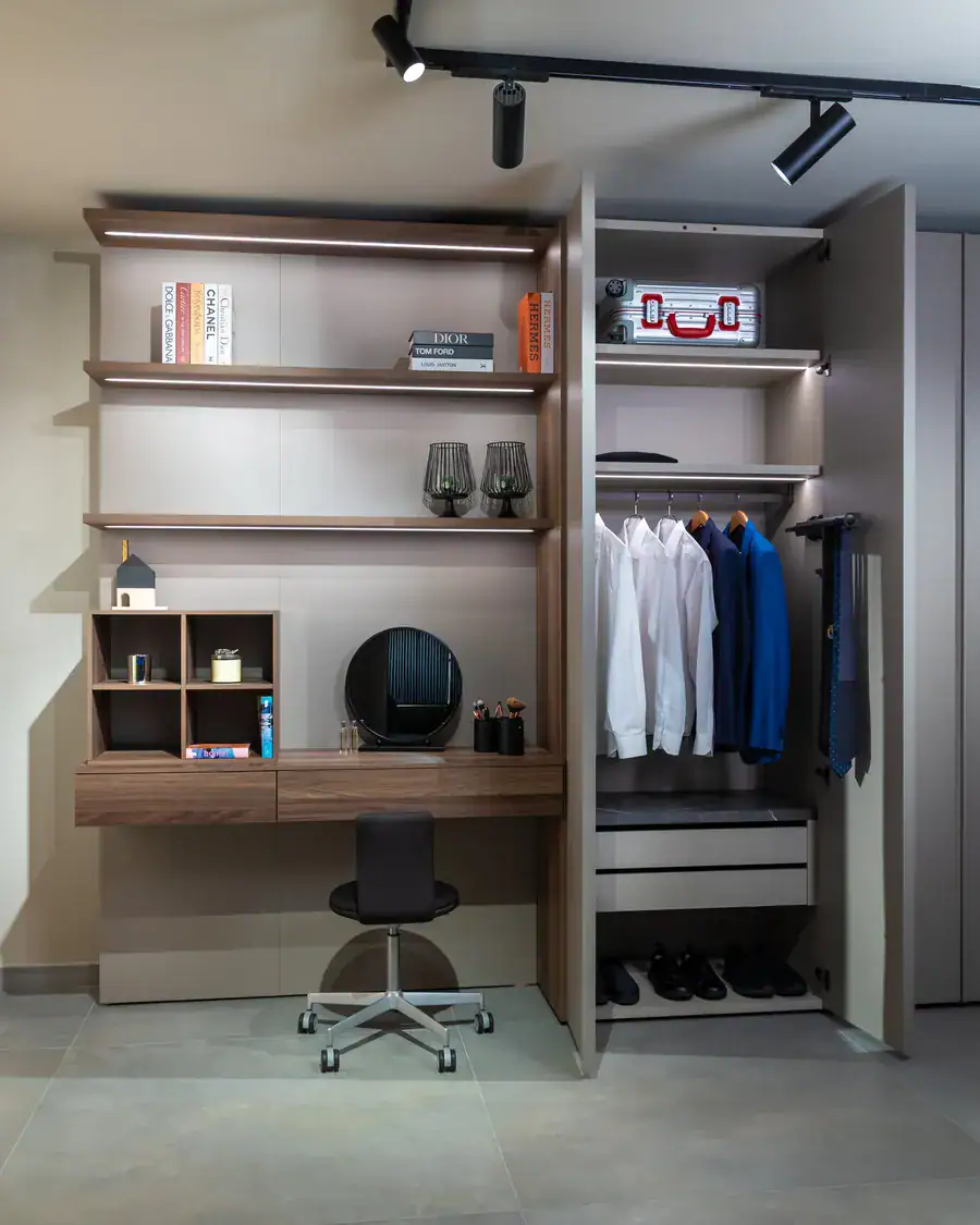 Built-in desk and shelving beside an open wardrobe
