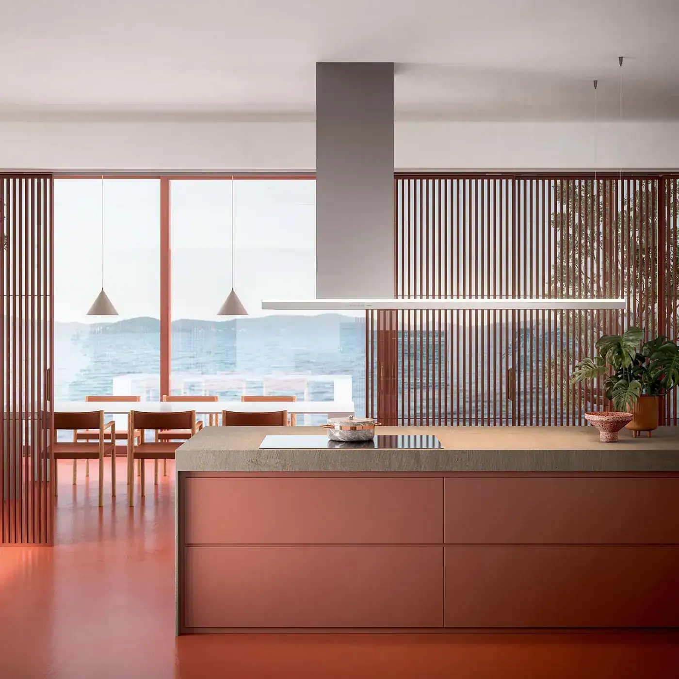 A kitchen island under a slim suspended cooker hood