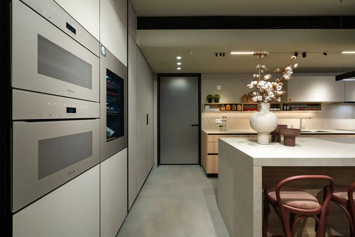 Built-in ovens and a wine cabinet beside a stone island